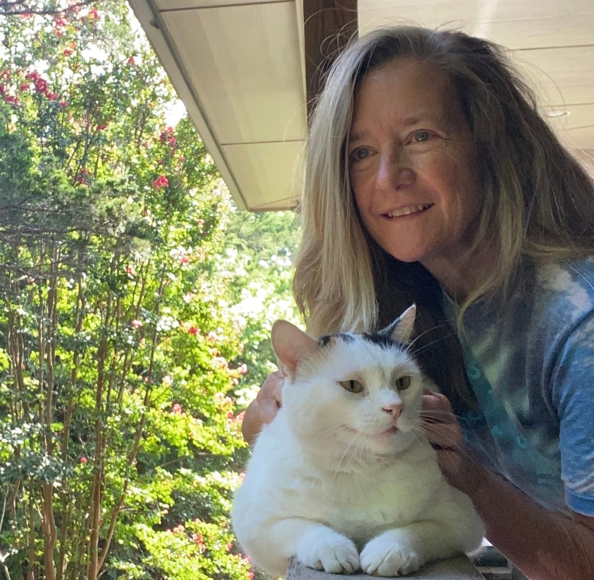 Coach Stephanie sitting outdoors with her cat on a sunny porch.